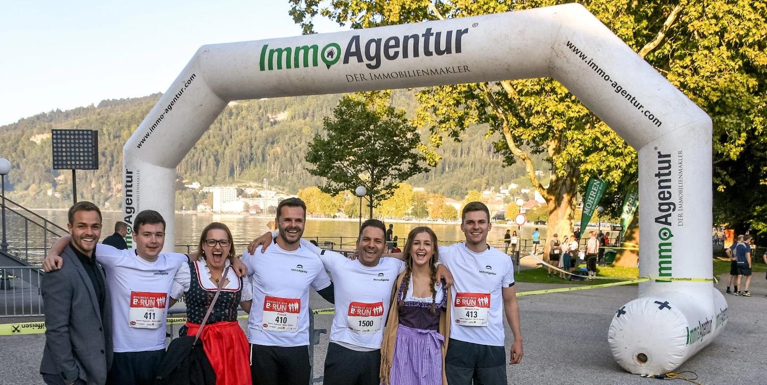 Team der IMMOAGENTUR in Laufshirts vor dem ImmoAgentur-Zielbogen am Bodenseeufer