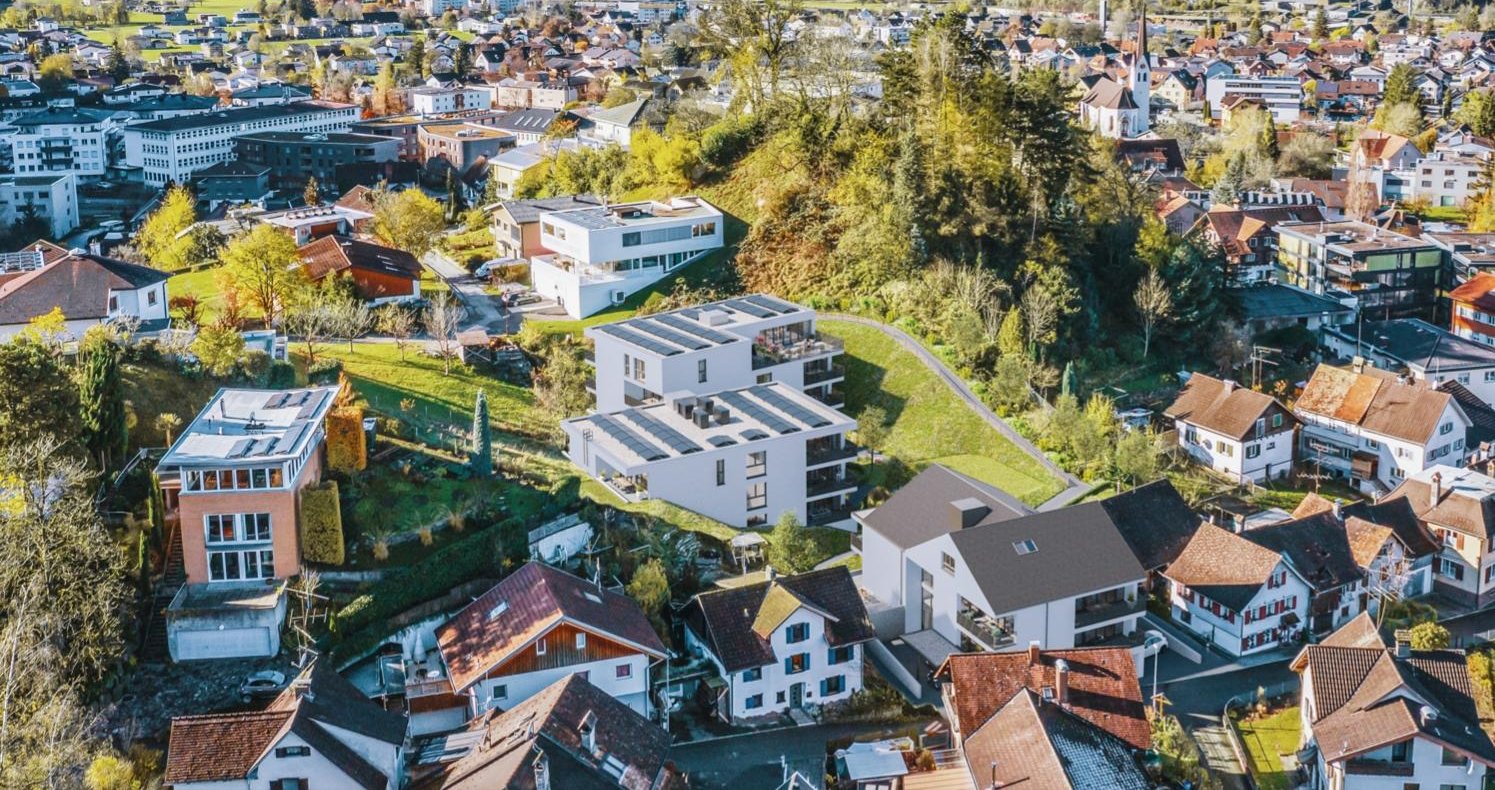 Luftbild einer Vorarlberger Gemeinde im Herbst mit neuen Wohnbauten am Hang