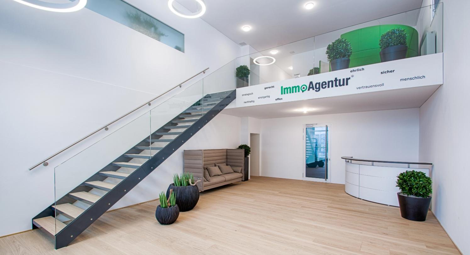 Eingangshalle der IMMOAGENTUR-Zentrale in Götzis mit Treppe, Galerie und Logo